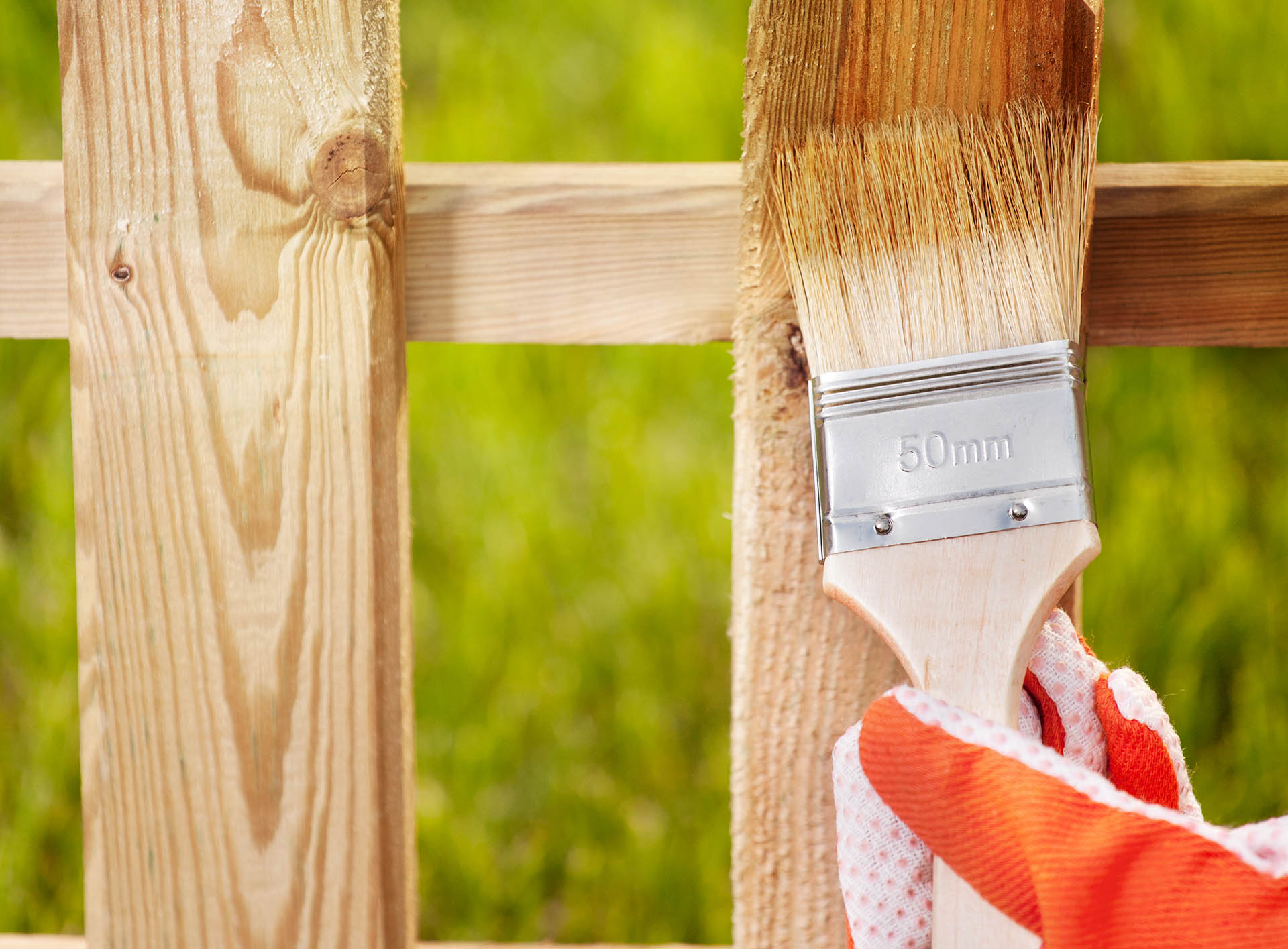 Pflegen und erhalten Sie Ihr Holz im Außenbereich. Zaunanstrich mit einem Pinsel und Lasur.